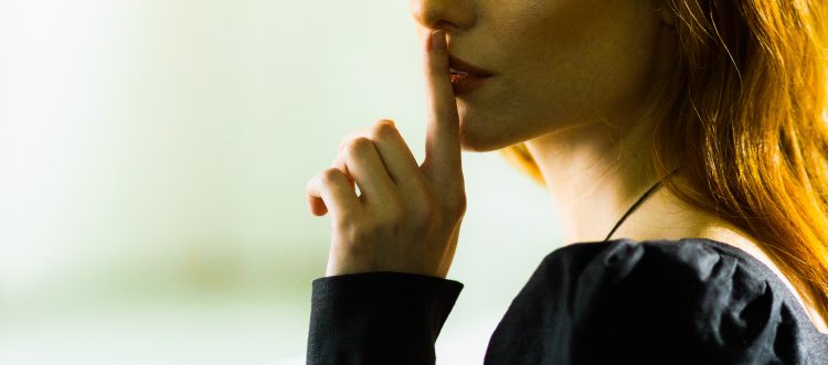 image of a lady with her finger to her mouth, symbolising "shush, keep it quiet, it's a secret.